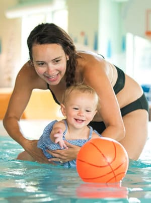 Mom and Baby playing with a ball in a pool at a water park