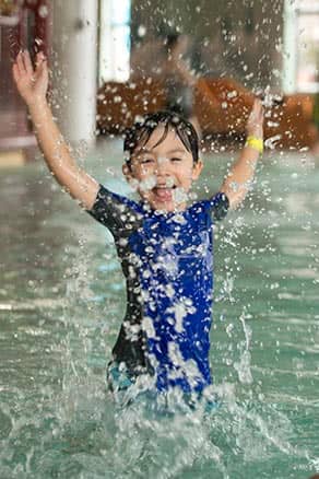 Toddler boy splashing in pool at waterpark