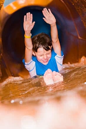 Boy with hands up on waterslide