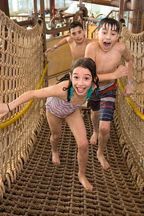 Kids running on rope bridge at water park
